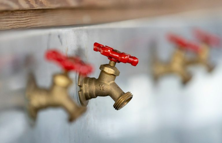 Legionella Awareness Metal taps with red handles arranged in a row.