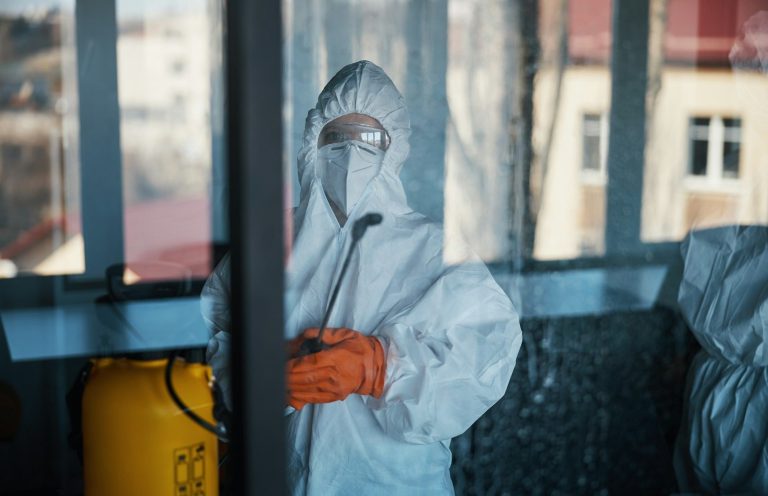 Asbestos Awareness A person in protective gear cleaning a glass surface.