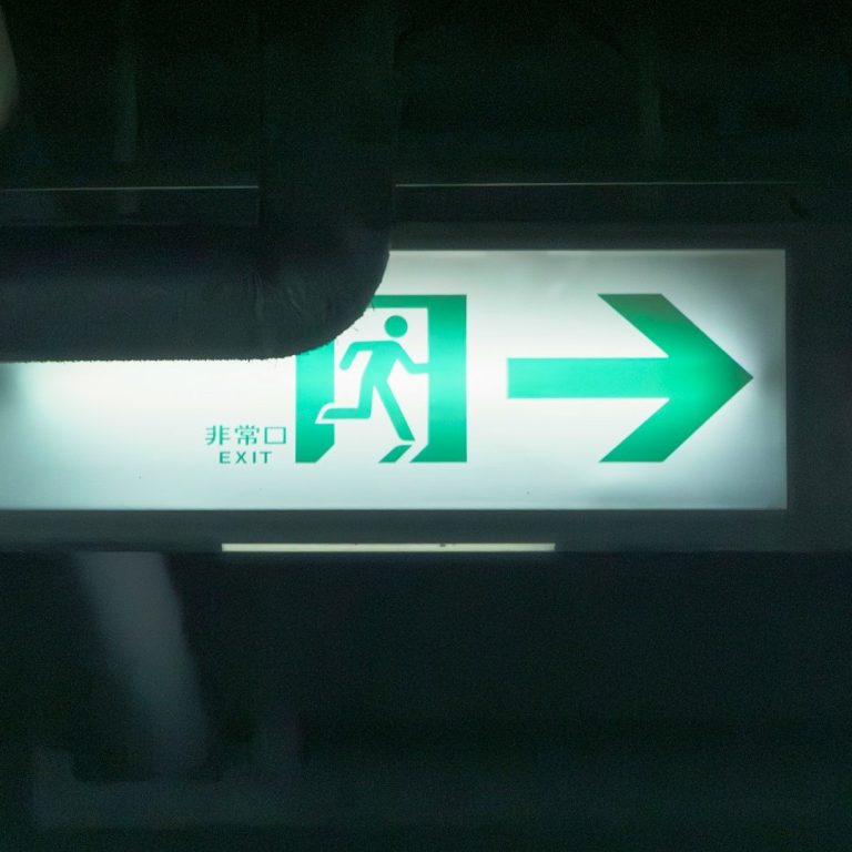 Green exit sign with an arrow pointing right and a figure running.